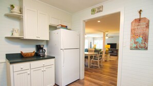 A kitchen with white cabinets, a refrigerator, and a coffee maker on the counter.