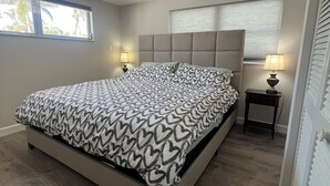 Ein Schlafzimmer mit Bett, Deckenventilator, Fenster und Nachttisch.