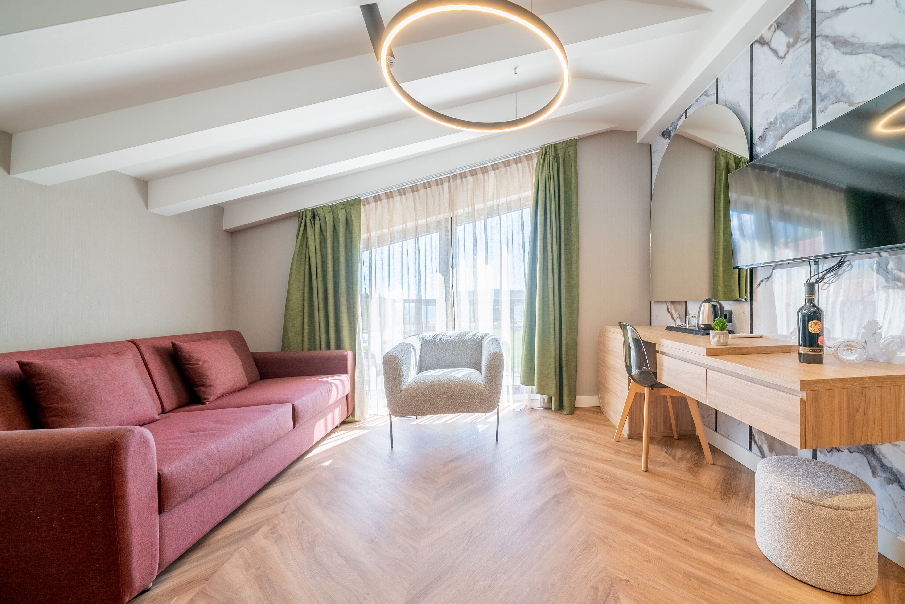A modern living room with a sofa, a chair, a wooden dining table, and a kitchen area with a TV and a bottle.