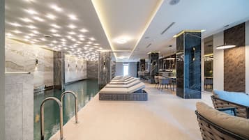 Una piscina techada, sillones reclinables de piscina