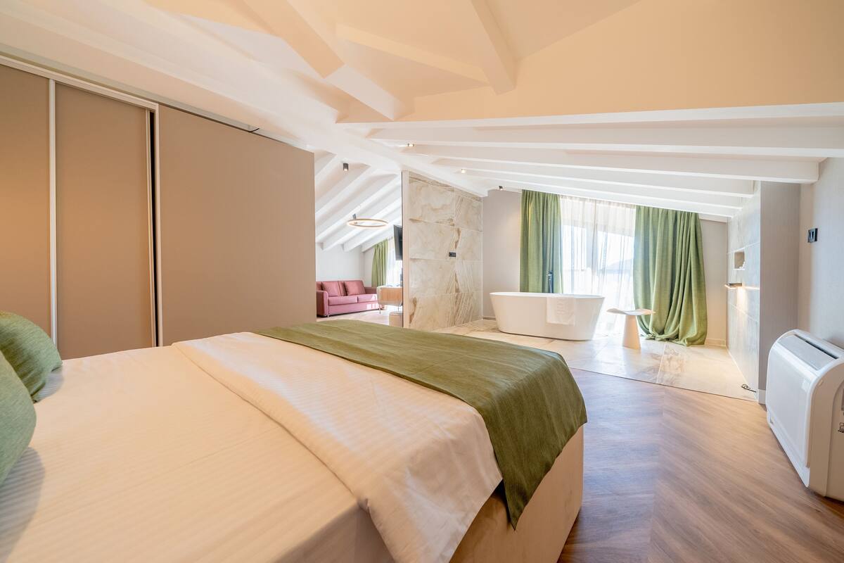 Un dormitorio moderno con una cama grande, un baño con bañera y vistas a la ciudad.