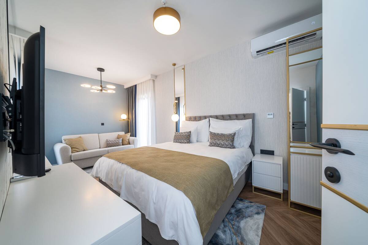 Una habitación de hotel moderna con cama, sofá, escritorio y armario.