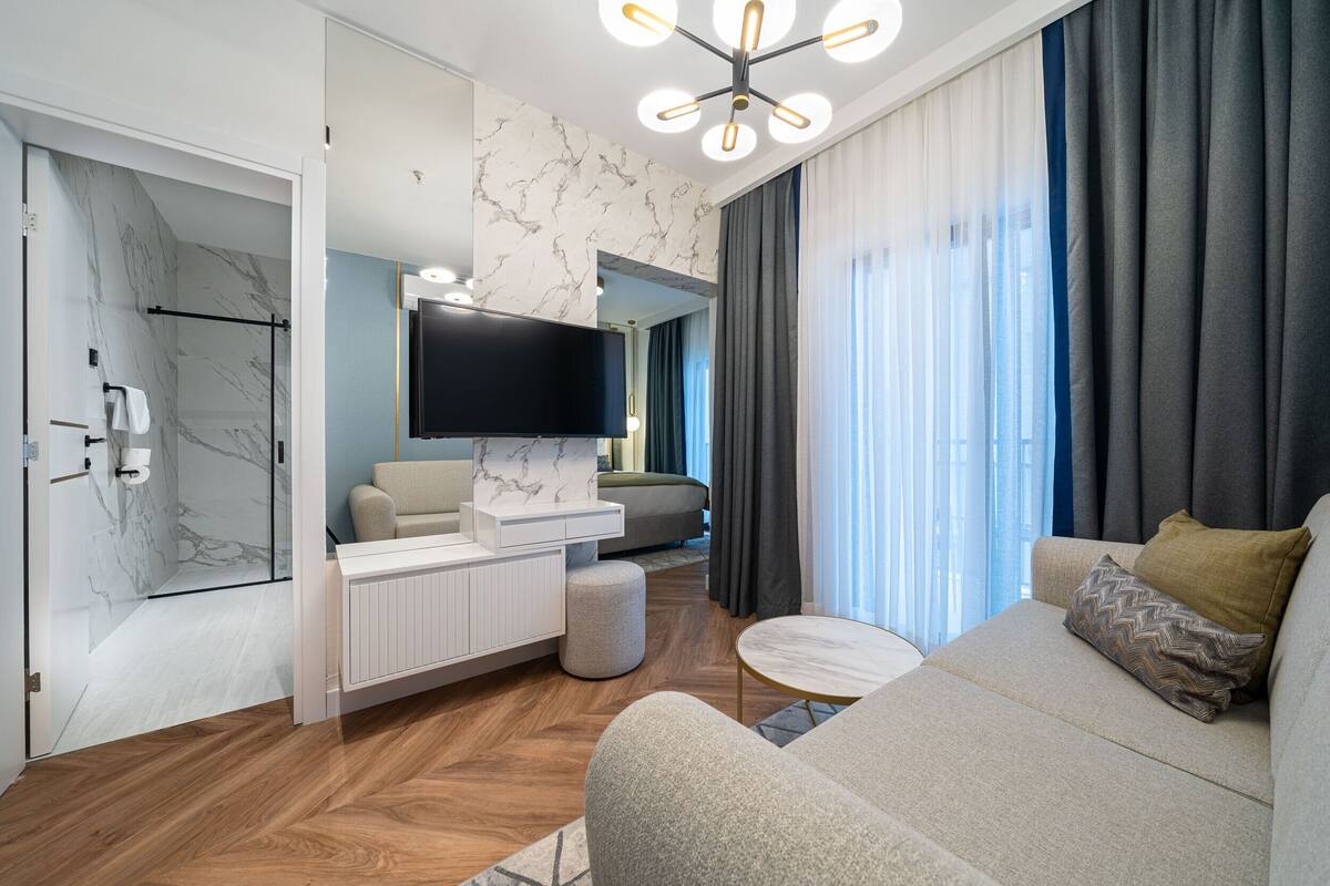 Una sala de estar moderna con un sofá, una mesa de centro, un televisor y una zona de estar con un banco acolchado.