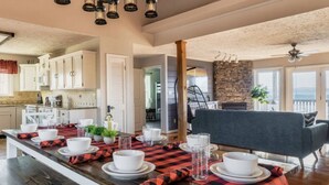 A spacious dining area with a long wooden table set for a meal, a stone accent wall, and a view of the outdoors.