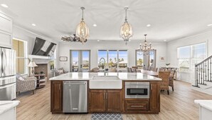 A spacious kitchen with a large island, stainless steel appliances, and pendant lighting. - The Shoreland Water-Front Home, Volleyball &Hottub (Gulf Shores)