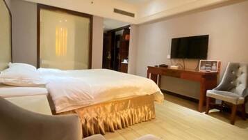 Habitación de hotel con una cama grande, un escritorio con silla, un televisor y un armario.