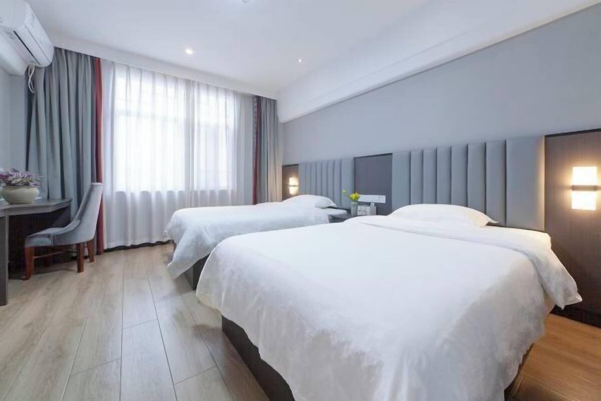 A hotel room with two beds, a desk, and a chair.