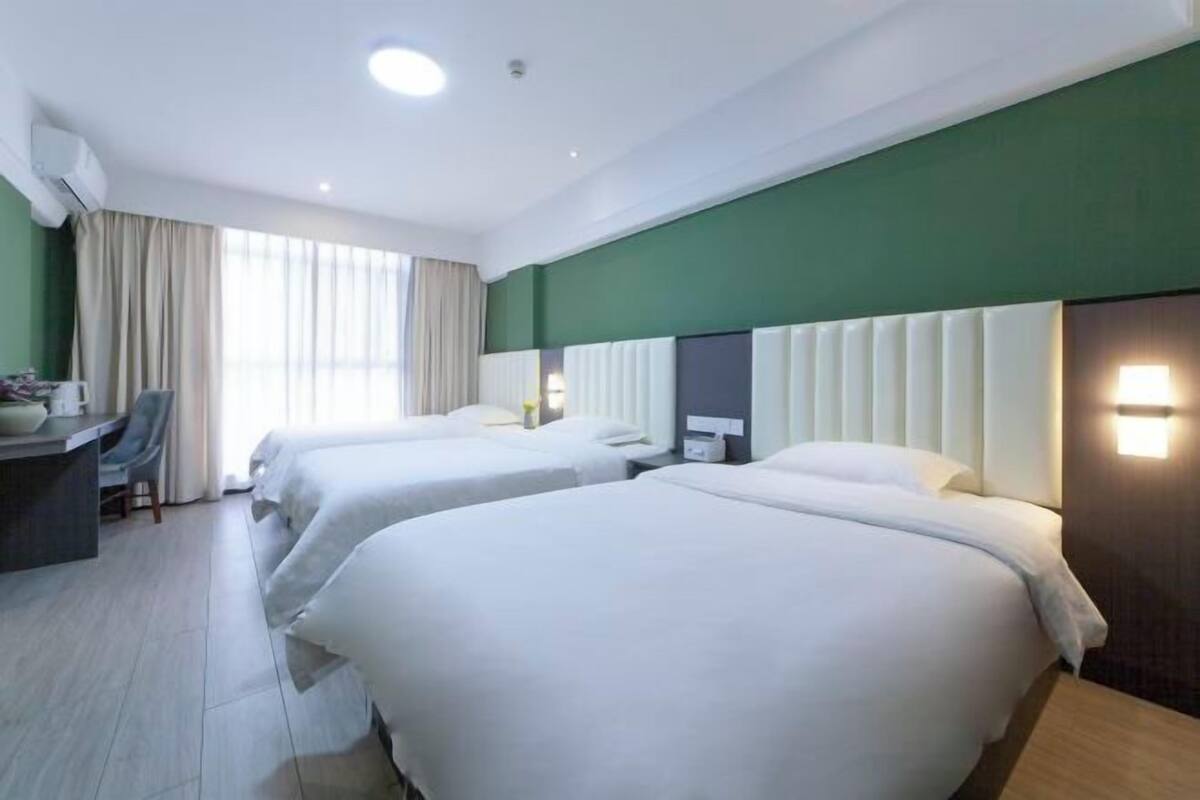 A hotel room with two beds, a desk, and a chair.