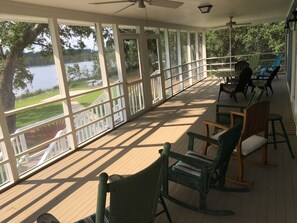 Un porche cubierto con vistas a un lago, terraza de madera y mobiliario exterior.