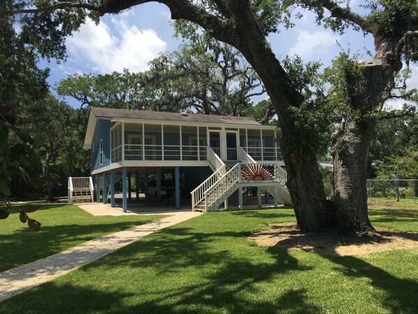 A two-story house with a covered porch and a staircase leading to a deck. - Beautiful , private Bon Secour riverfront home with spacious screened porch (Bon Secour)
