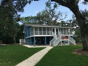 A two-story house with a covered porch and a staircase leading to the upper level. - Beautiful , private Bon Secour riverfront home with spacious screened porch (Bon Secour)