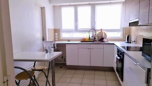 Eine moderne Küche mit weißen Schränken, einem großen Fenster und einem Essbereich mit Tisch und Stühlen.