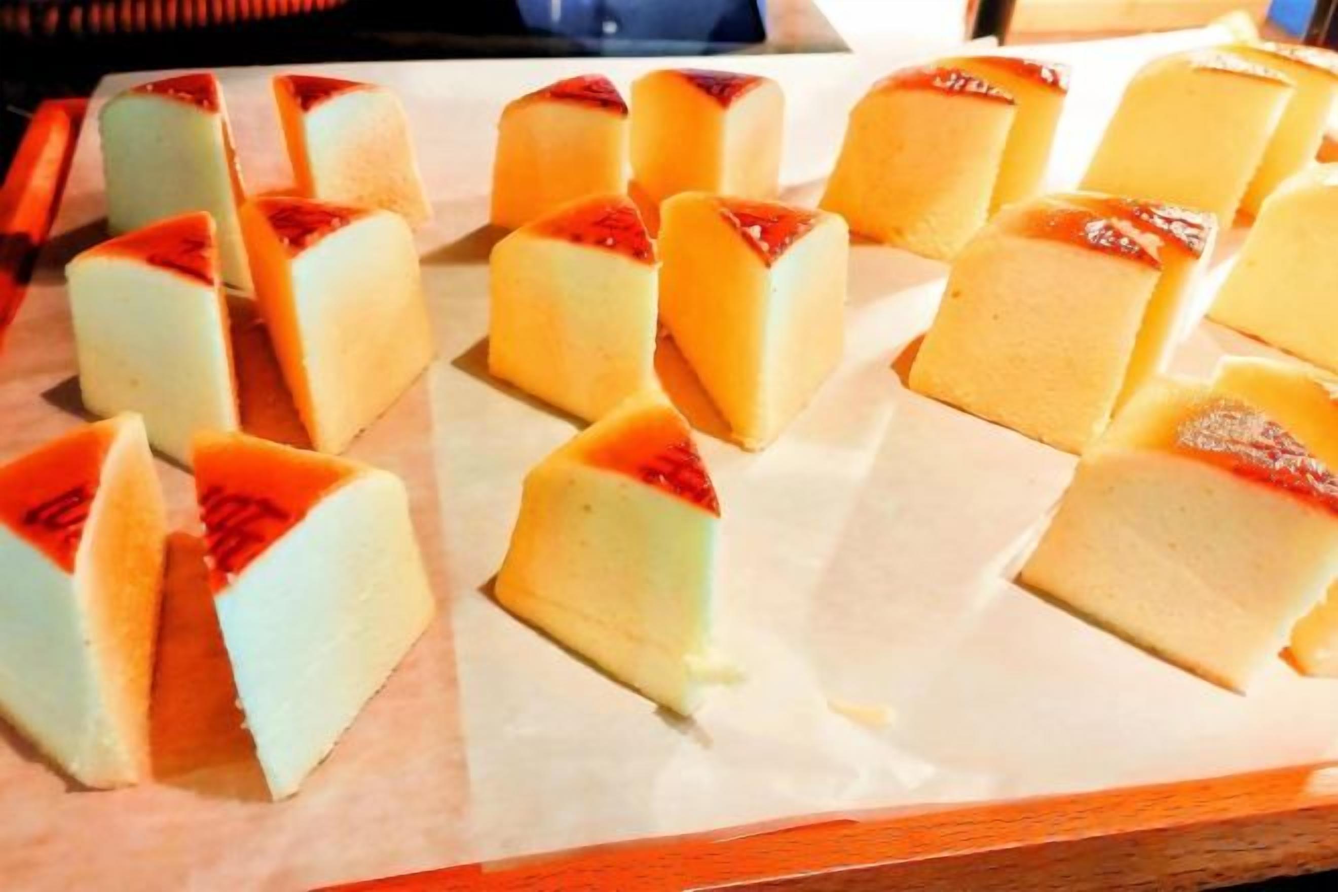 A tray of square-shaped desserts with a caramelized top, arranged on parchment paper.