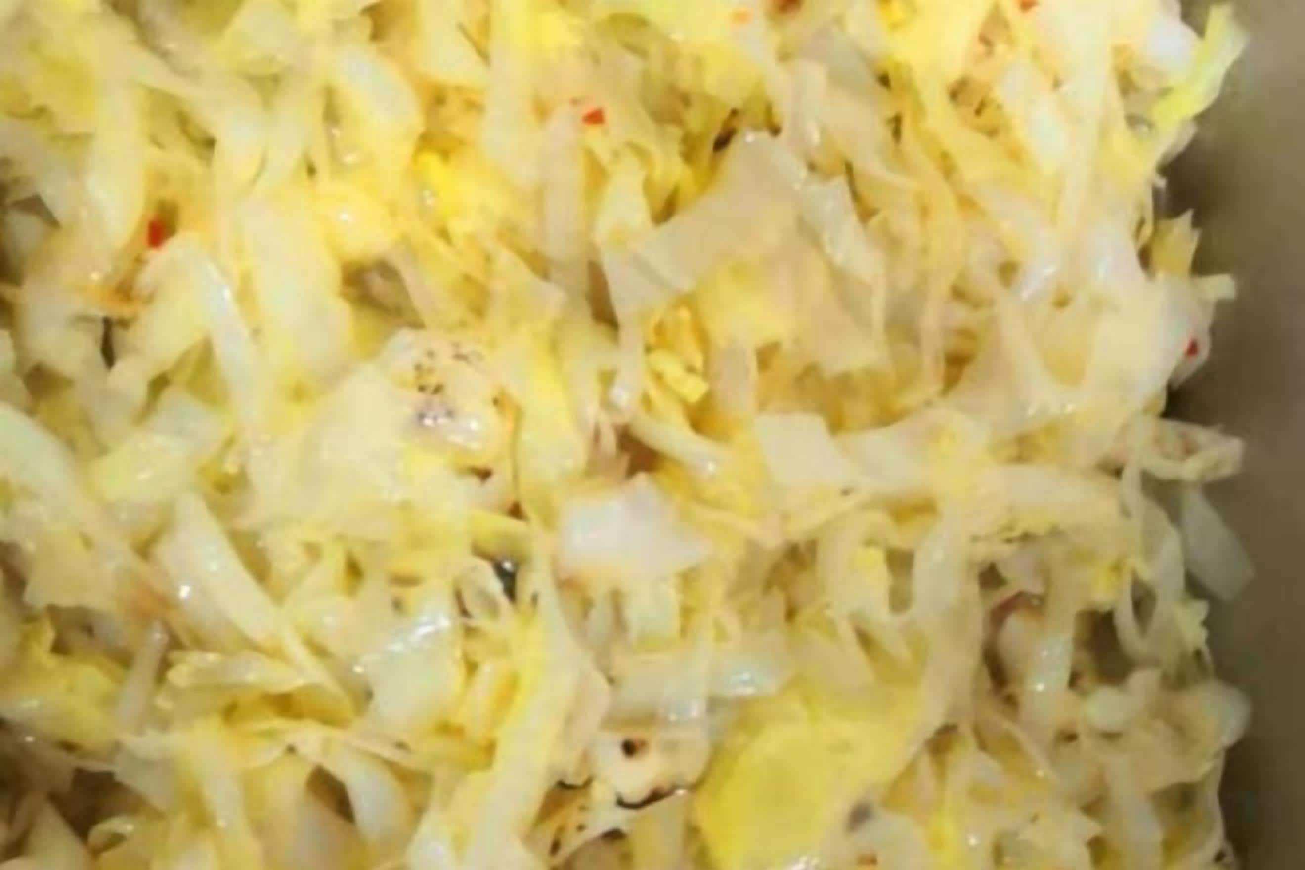 A close-up of a food dish with shredded ingredients, possibly cabbage or a similar vegetable, cooked with eggs.