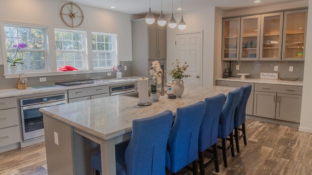 A modern kitchen with a central island, blue bar stools, and a clock on the wall. - Golden Lantern @ Acadia National Park, A/C, Spacious, Seafood (Tremont)