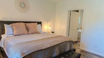 A neatly made bed with a headboard, a bedside lamp, and a bench at the foot of the bed.