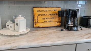 A kitchen with a coffee maker, a coffee grinder, and a sign that reads "Welcome to the Golden Ranger Coffee and Tea Bar."