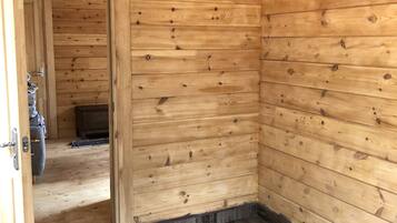 Interno di una baita in legno, con una porta in legno che dà su un'altra stanza, un pavimento in legno e un soffitto a vista.