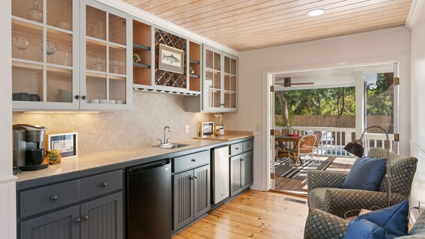 Una cocina con techo de madera, armarios empotrados y un comedor con silla y mesa estampada.
