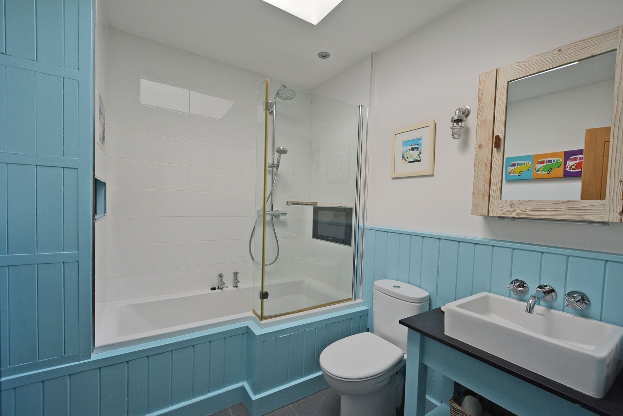 Un baño con ducha de vidrio, inodoro y lavabo con espejo.