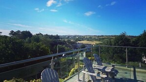 A balcony with chairs overlooking a scenic landscape. - Penmorfa - Sublime Abersoch retreat with roof terrace, 80m from beach, great for surfing (Abersoch)