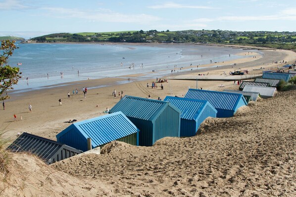 A beach with people and a row of blue beach huts.