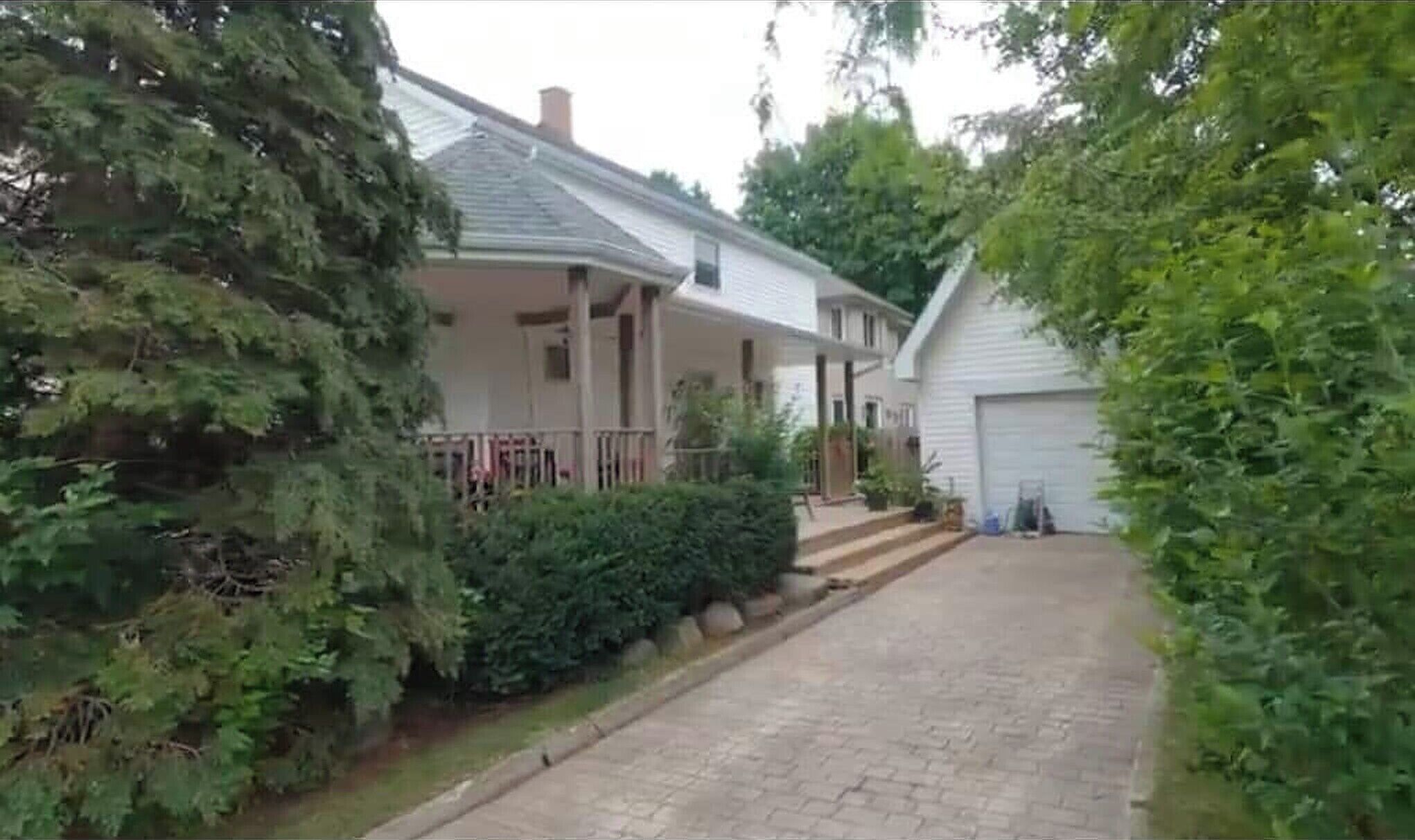 Eine Wohnstraße mit zwei Häusern, eines davon mit Veranda und Garage.