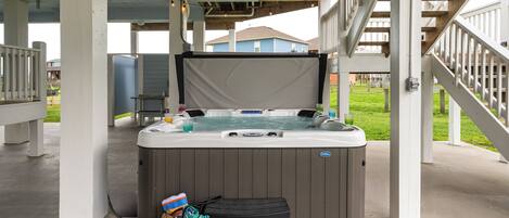 A hot tub with a cover, a small table, and a trash bin.