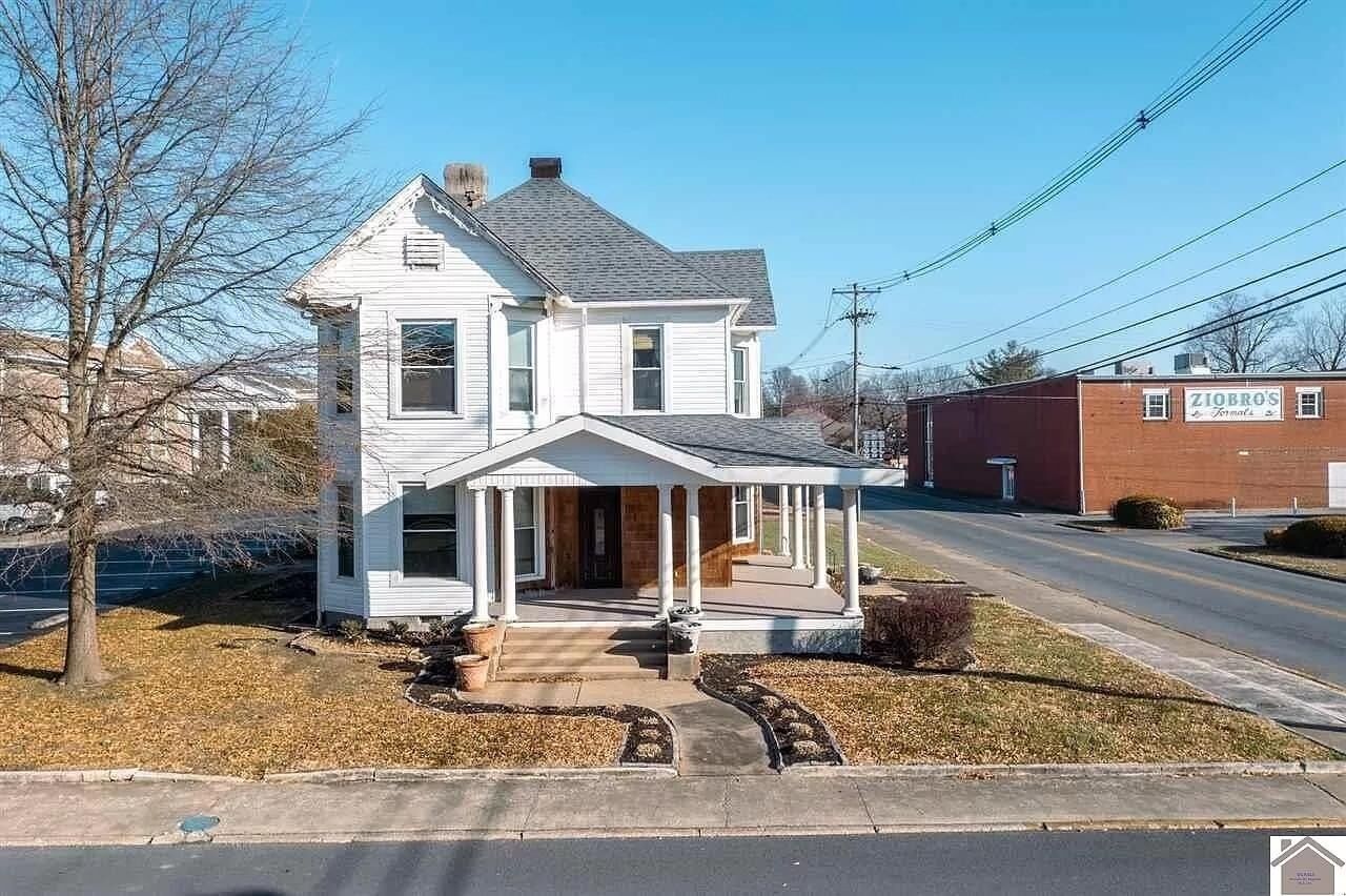 Een wit huis met twee verdiepingen, een veranda en een garage.