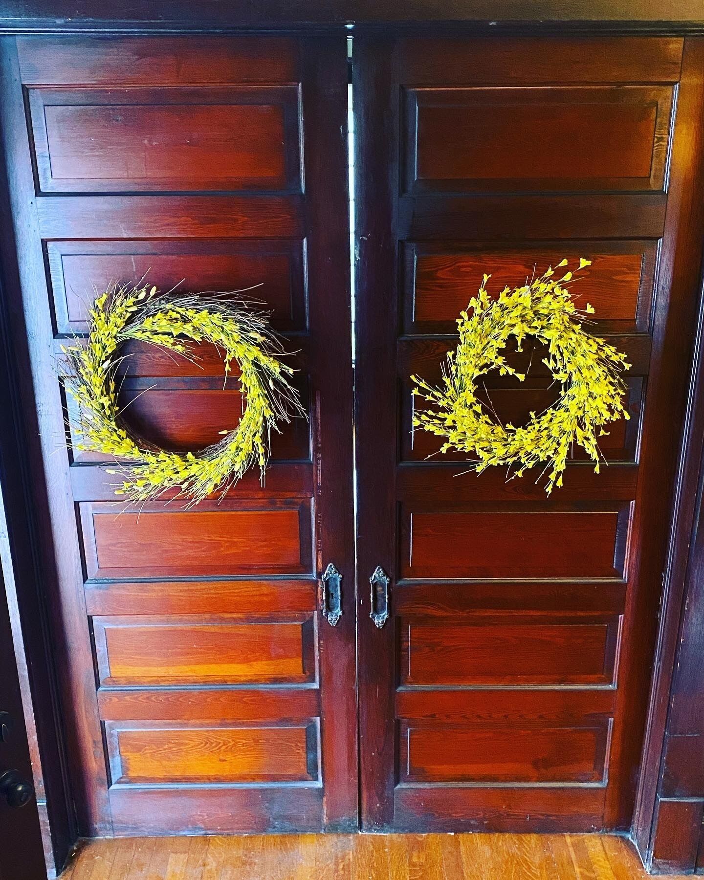 A wooden double door with two wreaths placed on the handles.