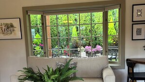 A living room with a large window, a sofa, a coffee table, and a potted plant. - Fabulous Bungalow, 1 block from 5th Street Market (Eugene)