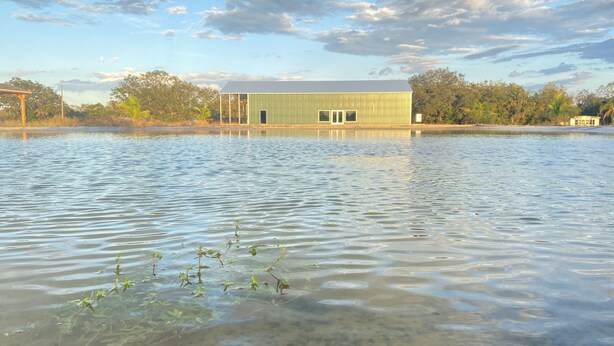 Um edifício parcialmente submerso em água, com céu claro.
