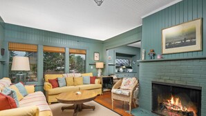 A cozy living room with a fireplace, a sofa set, and a dining area.
