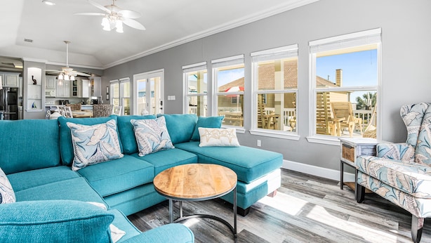 A spacious living room with a teal sectional sofa, a round wooden coffee table, and a patterned armchair. - Family Fun! ⛱ Walk to Beach ♥Pet-Friendly (Crystal Beach)