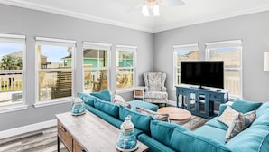 A spacious living room with teal sofas, a large flat-screen TV, and a ceiling fan. - Family Fun! ⛱ Walk to Beach ♥Pet-Friendly (Crystal Beach)
