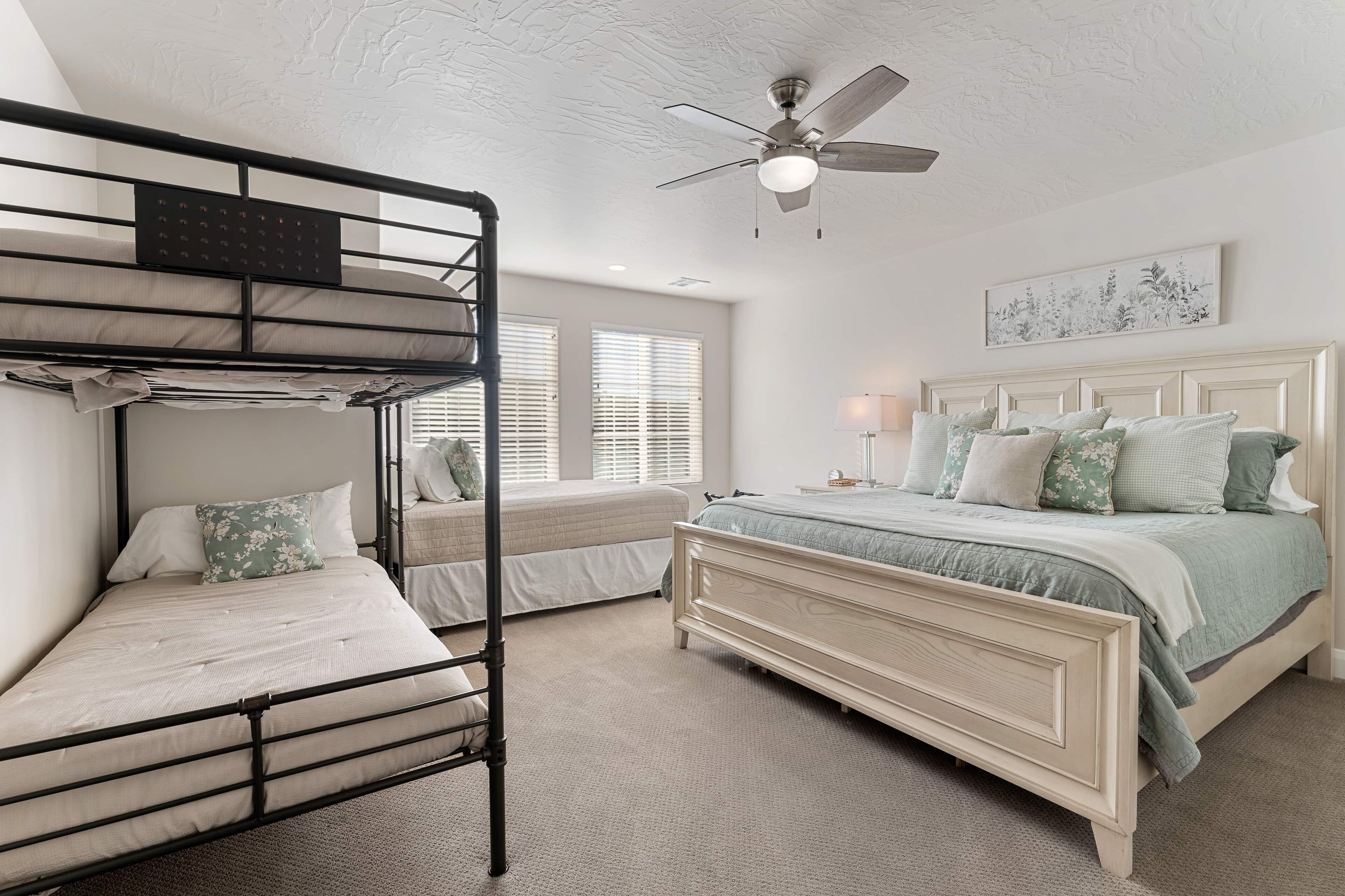 A bedroom with bunk beds, a single bed, a ceiling fan, and a window with blinds.