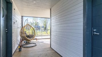 Moderni sisustus, jossa on puulattia, rottinkituoli ja näkymä suurista ikkunoista.