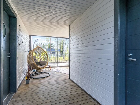 Un intérieur moderne avec un plancher en bois, un fauteuil en osier et une vue dégagée grâce à de grandes fenêtres.