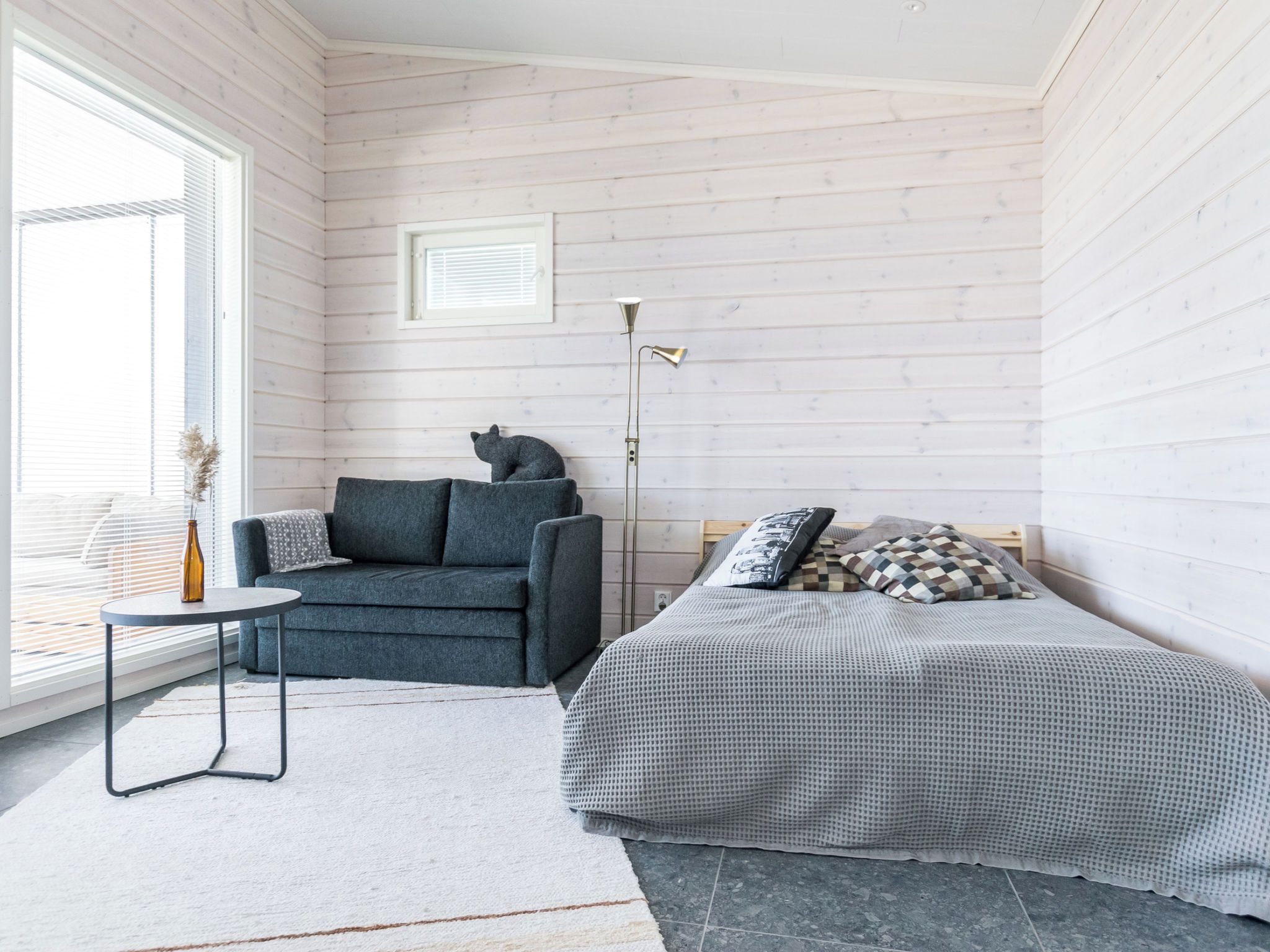 Ein Schlafzimmer mit einem Bett, einem Sessel, einem kleinen Tisch und einer Stehlampe.