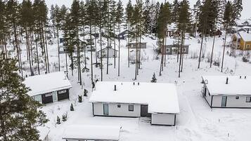 Asuinalue, jossa on useita taloja, ja jonka ympärillä on lumipeitteinen maa ja puita.