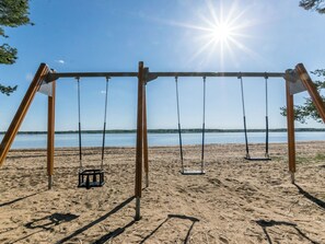 Une balançoire installée sur la plage, offrant une vue dégagée sur le lac et le ciel.