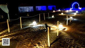 A nighttime outdoor area with illuminated structures and a QR code on the ground.