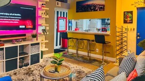 Una sala de estar moderna con un televisor de pantalla plana, una zona de cocina y un comedor.