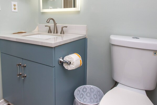 A bathroom with a white sink, a toilet, and a cabinet with a towel dispenser.