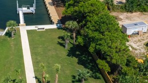 An aerial view of a property with a dock, a grassy area, and a large tree. - Next to Kayak Park |1st Floor Condo |Short Walk to Beach |Beach Cart, 2 Chairs & Umbrella |Dogs Ok (Fort Walton Beach)