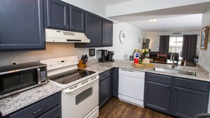 A modern kitchen with dark cabinets, a microwave, stove, dishwasher, and a coffee maker. - Next to Kayak Park |1st Floor Condo |Short Walk to Beach |Beach Cart, 2 Chairs & Umbrella |Dogs Ok (Fort Walton Beach)