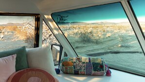 A bedroom with a skylight, a bed with pillows, a quilt, and a view of a desert landscape. - Private Luxury Glamping w/Celestial Views (Joshua Tree)
