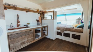 A compact kitchen with a wooden countertop, built-in shelves, and a window seat with cushions. - Private Luxury Glamping w/Celestial Views (Joshua Tree)