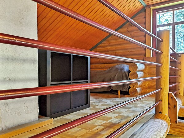A wooden interior with a fireplace, a window with a view, and a checkered floor.