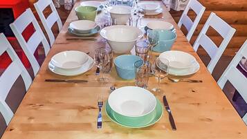 A wooden dining table set with plates, bowls, glasses, and cutlery.